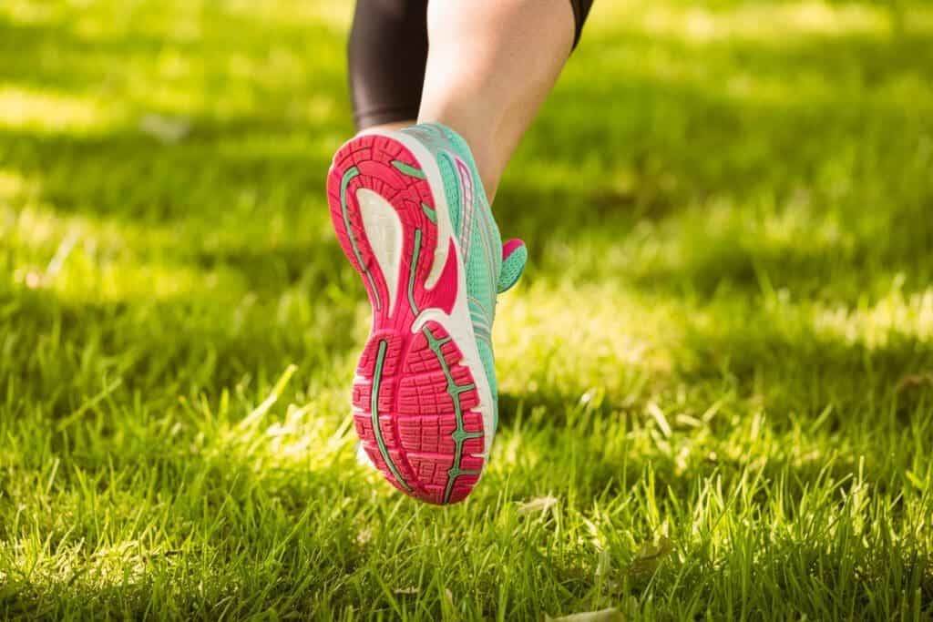 15949292 woman in running shoes running on grass
