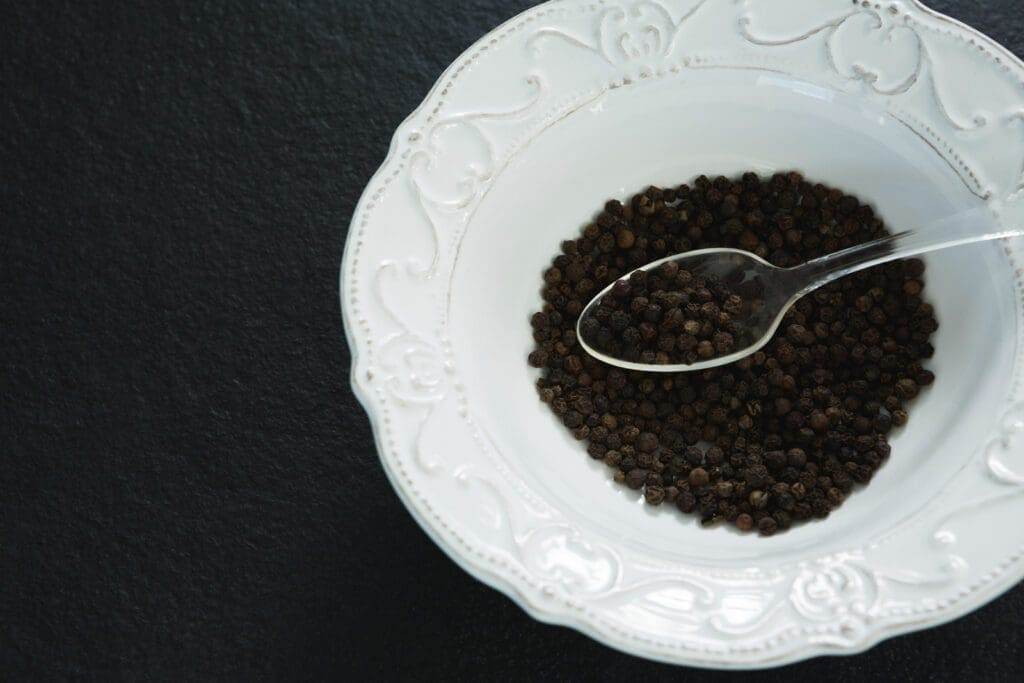 29621496 black pepper in spoon and bowl