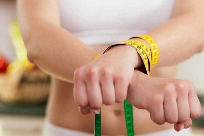 Woman handcuffed by a tape measure - symbol for eating disorder