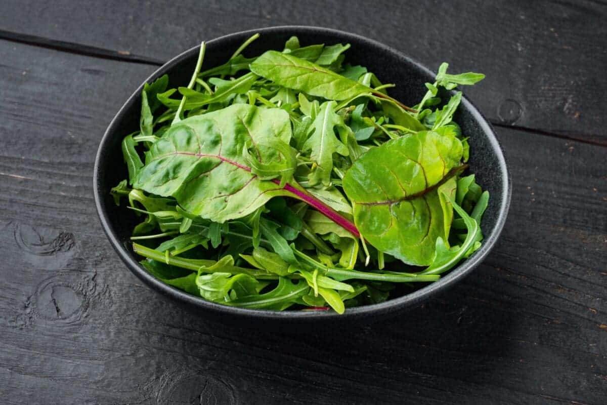 37527974 arugula chard herbs mix on black wooden table background scaled