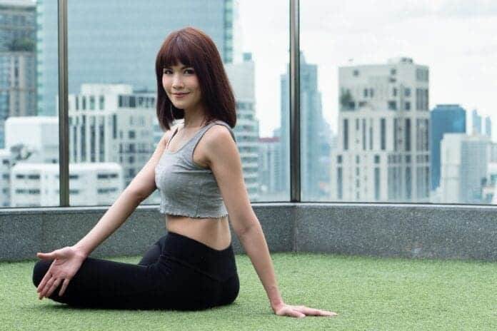 Woman practicing yoga core body twisting pose in urban environment, belly pose for internal digestive organ benefit