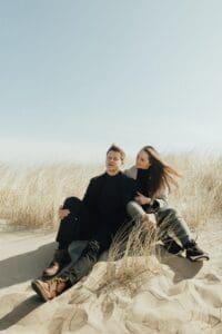 A couple sitting on a dune.