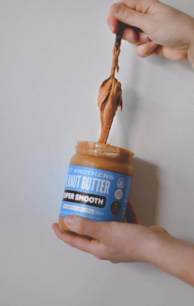 A hand taking out peanut butter from the jar.