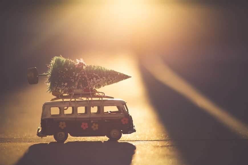 A miniature van in the sunrise background with a Christmas tree on it.
