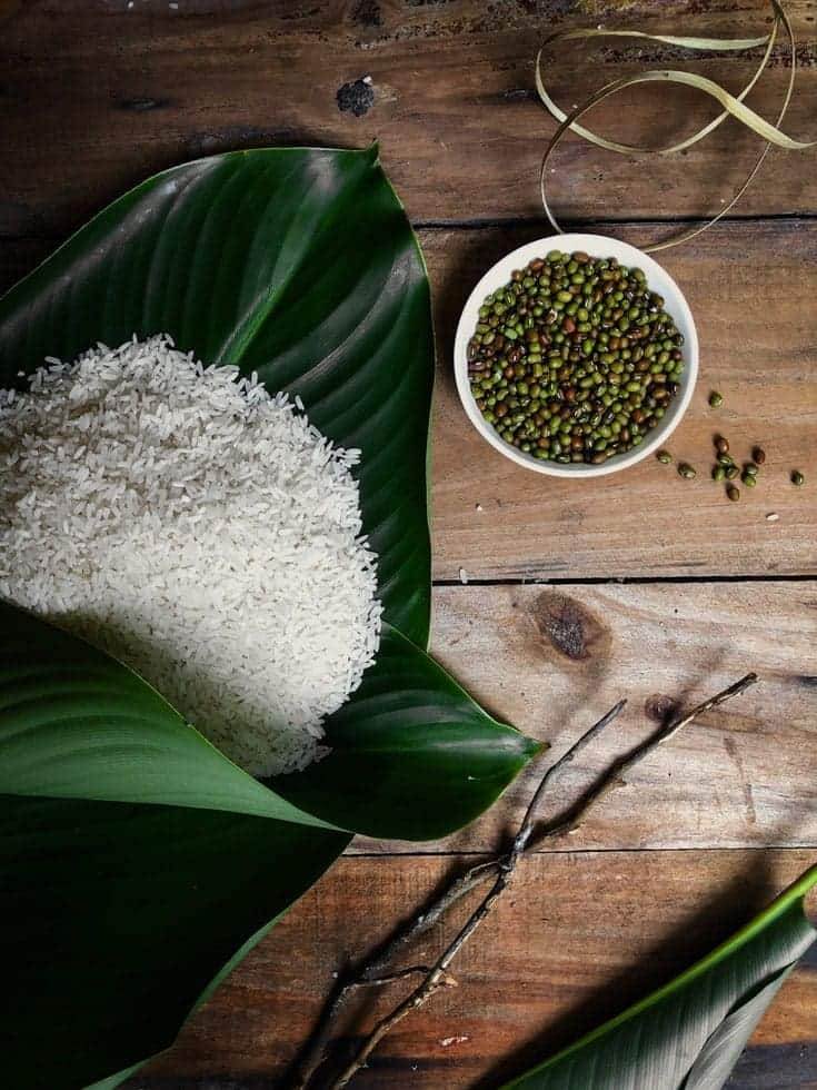 Rice on a leaf beside a bowl of mung beans. 