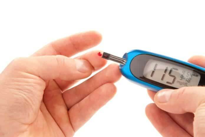 Diabetic patient doing glucose level blood test using ultra mini glucometer and small drop of blood from finger and test strips isolated on a white background.